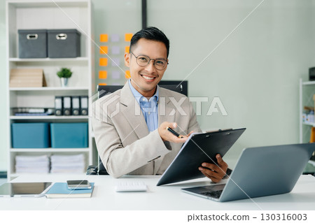 Asian businessman typing laptop and tablet Placed at the table at the office Asian businessman typing laptop and tablet Placed at the table at the office 130316003