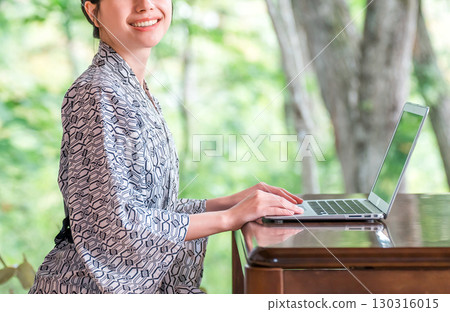 A woman in a yukata working on a computer in a room at a hot spring inn 130316015