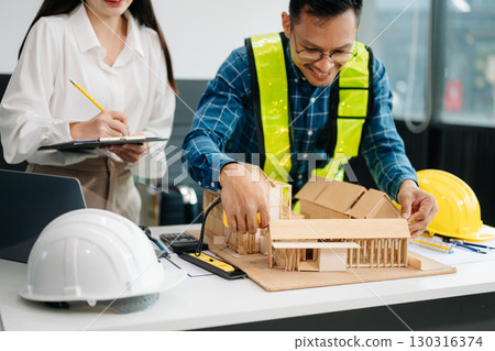 Engineer Teamwork Meeting, Drawing working on blueprint meeting for project working with partner on model building at company office Engineer Teamwork Meeting, Drawing working on blueprint meeting for project working with partner on model building at company office 130316374