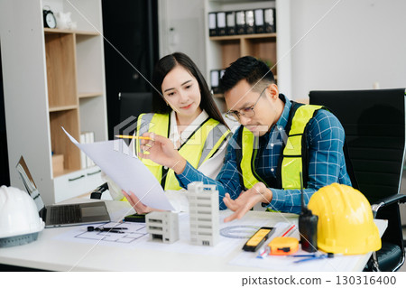Creative architect projecting on the big drawings with architectural project at construction site at desk 130316400
