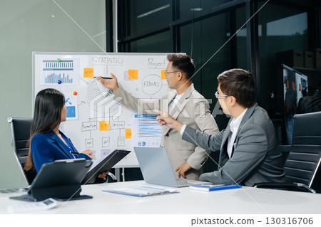 Office colleagues have a casual discussion. During a meeting in a conference room, a group of Asian business teem sit in the conference room 130316706