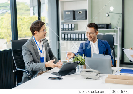 Happy Asian businesspeople while collaborating on a new project. using a laptop and tablet Happy Asian businesspeople while collaborating on a new project. using a laptop and tablet 130316783