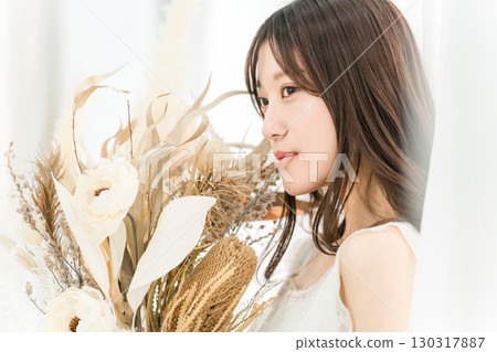 A stylish woman holding a swag of dried flowers A stylish woman holding a swag of dried flowers 130317887