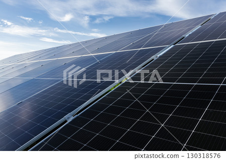 Solar panels absorbing sunlight under a cloudy blue sky Solar panels absorbing sunlight under a cloudy blue sky 130318576
