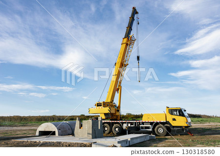 Mobile crane lifting concrete blocks during infrastructure construction under blue sky 130318580