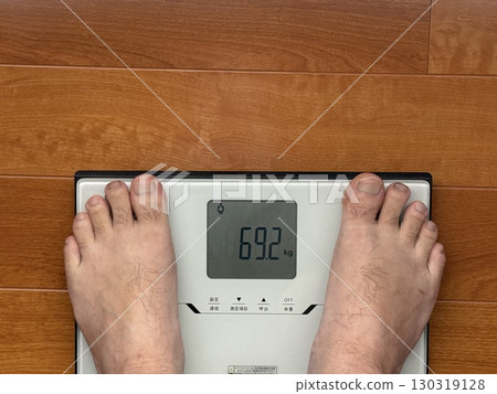A middle-aged man standing on a weight scale 130319128