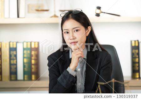 Confident Lawyer. Young female lawyer posing thoughtfully in office with gavel. 130319337