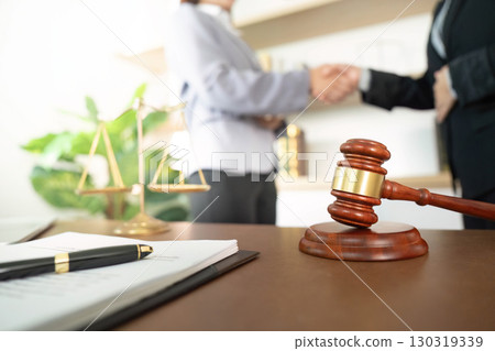 Legal Agreement. Two lawyers shaking hands with gavel and scales in foreground. 130319339