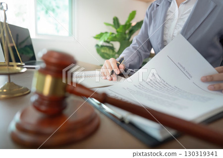 Legal Documentation. Businesswoman signing contract with gavel in foreground. 130319341