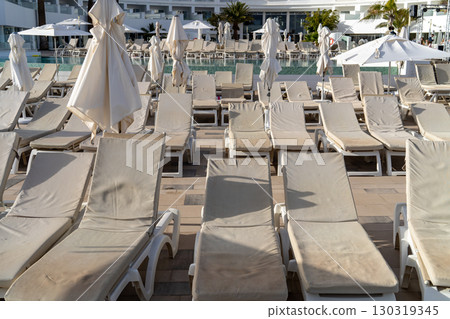 Empty sunbeds and parasols are arranged by a swimming pool at a resort in Lanzarote, Spain. Empty sunbeds and parasols are arranged by a swimming pool at a resort in Lanzarote, Spain. 130319345