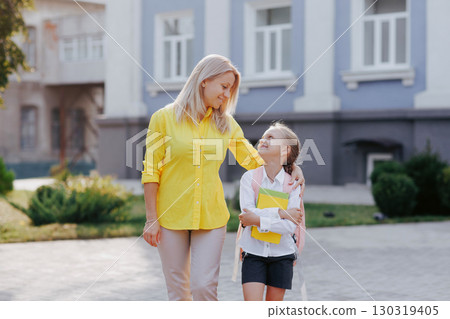 Happy mother and daughter walk to school together, back to school, family bonding, education and support concept outdoors. 130319405