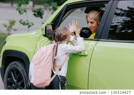 Mother and daughter share an emotional farewell through the car window on the first day back to school, showing encouragement and support. Mother and daughter share an emotional farewell through the car window on the first day back to school, showing encouragement and support. 130319427