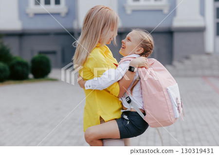 Happy mother hugs her daughter before school, family bonding and education, back to school, parent and child together. 130319431