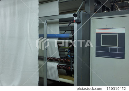 Automated textile machine processes fabric in modern factory, showcasing advanced manufacturing and efficiency Automated textile machine processes fabric in modern factory, showcasing advanced manufacturing and efficiency 130319452