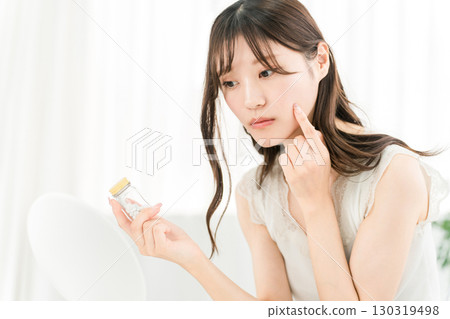 亞洲女性拿著一瓶藥物/補充劑時擔心 130319498