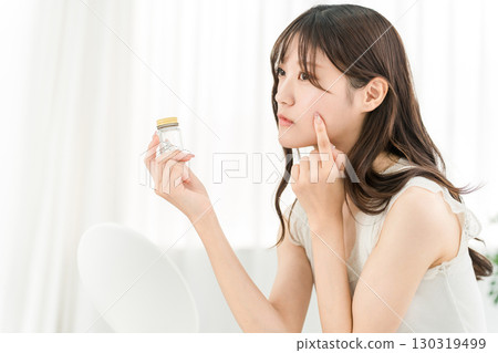 亞洲女性拿著一瓶藥物/補充劑時擔心 130319499