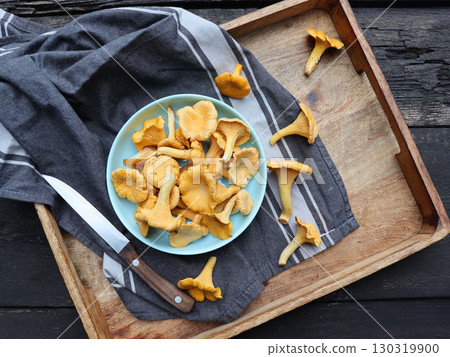 Bowl of chanterelle mushrooms on wooden background Cantharellus cibarius, commonly known as the chanterelle, golden chanterelle or girolle Bowl of chanterelle mushrooms on wooden background Cantharellus cibarius, commonly known as the chanterelle, golden chanterelle or girolle 130319900