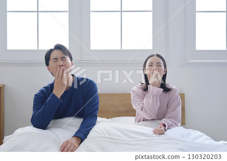 Couple yawning in bed in the morning due to lack of sleep Couple yawning in bed in the morning due to lack of sleep 130320203