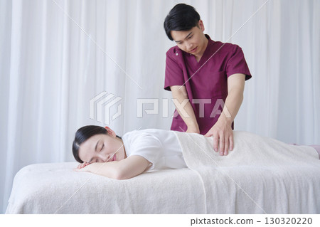 Female masseuse giving back massage Female masseuse giving back massage 130320220