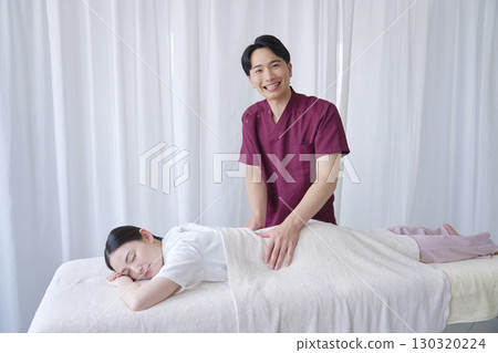 Portrait of a masseuse giving a back massage, looking at the camera 130320224