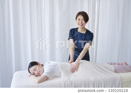 Portrait of a female masseuse giving a back massage Portrait of a female masseuse giving a back massage 130320228