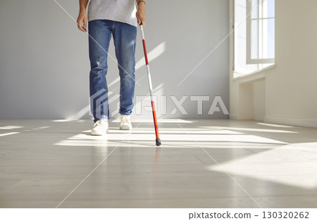 Deaf and visually impaired man is walking with a red white cane indoors, at home 130320262