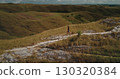 Tourist walking along a scenic path in the Sumba hills of Indonesia, soaking in the breathtaking landscape on a sunny day while enjoying a refreshing hike through the wilderness 130320384