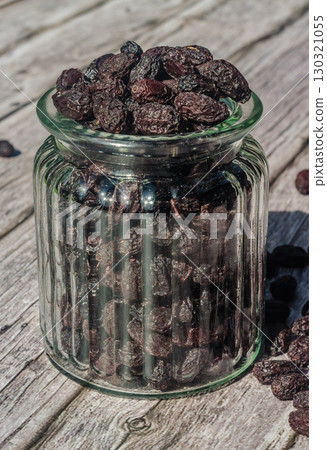 Close-up of a glass jar filled with dried cornelian cherryl , standing on a weathered wooden surface. Perfect for food, nutrition, and healthy eating concepts. High quality photo Close-up of a glass jar filled with dried cornelian cherryl , standing on a weathered wooden surface. Perfect for food, nutrition, and healthy eating concepts. High quality photo 130321055