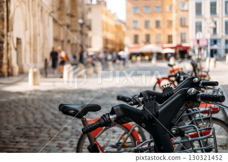Row of bicycles parked on cobblestone street in a European city with blurred pedestrians in the background. Micro mobility, urban mobility, eco transit, low carbon living Row of bicycles parked on cobblestone street in a European city with blurred pedestrians in the background. Micro mobility, urban mobility, eco transit, low carbon living 130321452