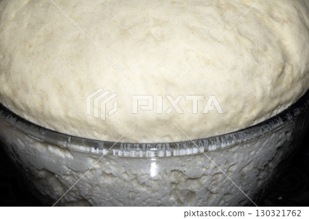 Close up of pizza bread dough that has risen over the glass bowl uncooked 130321762