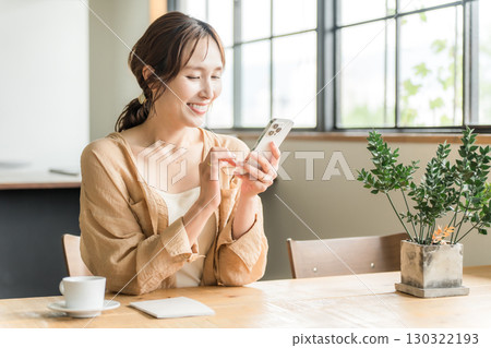 Young Asian woman looking at her smartphone while drinking coffee in a cafe (meeting) 130322193