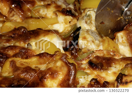 Close up of home made pizza with fresh dough and toppings cooked and being cut into slices 130322270