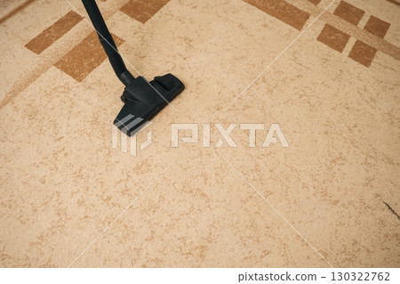 Vacuum cleaner removing dust and dirt from beige carpet during home cleaning, promoting hygiene and maintaining clean fresh living space. Concept of domestic work, housekeeping and household. Vacuum cleaner removing dust and dirt from beige carpet during home cleaning, promoting hygiene and maintaining clean fresh living space. Concept of domestic work, housekeeping and household. 130322762