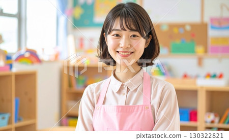 A woman with a short bob smiles gently in a pastel pink apron 130322821