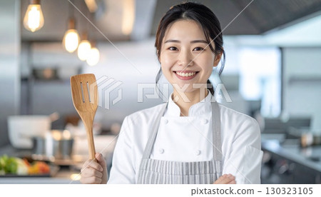 Over-the-shoulder portrait of a Japanese woman with a restaurant kitchen in the background. 130323105