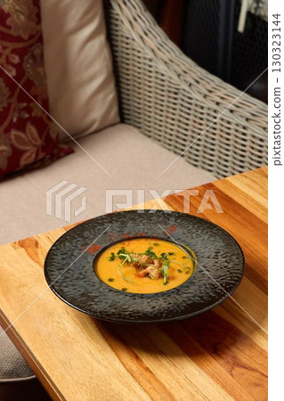 A Delicious and Creamy Soup is Beautifully Served in an Elegant Bowl on a Charming Wooden Table A Delicious and Creamy Soup is Beautifully Served in an Elegant Bowl on a Charming Wooden Table 130323144