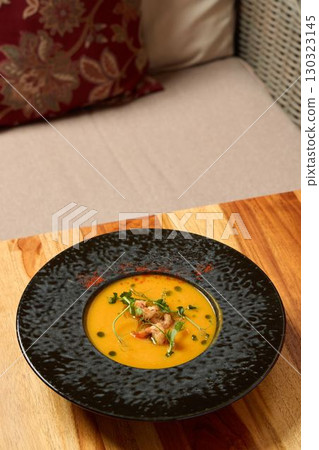 Indulge in Gourmet Pumpkin Soup presented in an Elegant Black Bowl, perfect for dining 130323145
