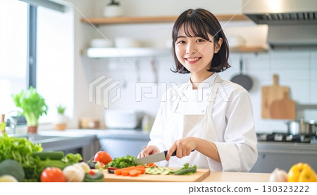 A woman with short bob cooking in a white apron and jacket 130323222