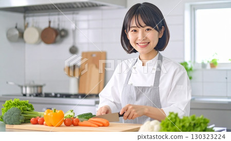 A woman with short bob cooking in a white apron and jacket 130323224