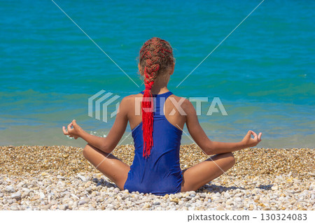 Girl back in lotus pose on pebble beach with sea background 130324083