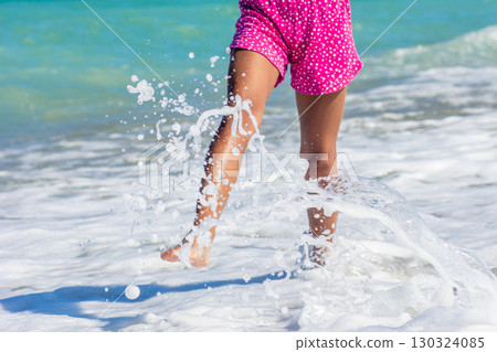 Child playing in sea foam at the beach 130324085