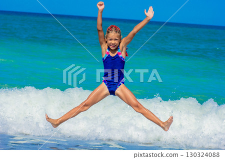 Joyful girl jumping on the beach in front of the sea 130324088