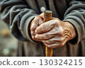 CloseUp of Elderly Hands Holding a Wooden Cane 130324215