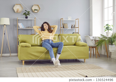 Happy girl relaxing on sofa after work at home Happy girl relaxing on sofa after work at home 130324496