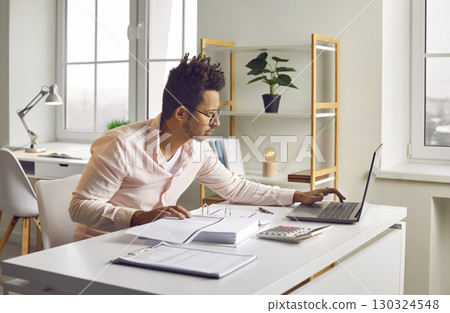 Businessman sitting at laptop computer checking balance and costs 130324548