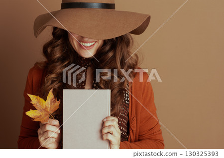 Cheerful Woman in Hat with Book and Autumn Leaf 130325393