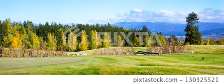 Vibrant nature panorama with stones, colorful green, yellow autumn trees, bridge and grass field 130325521