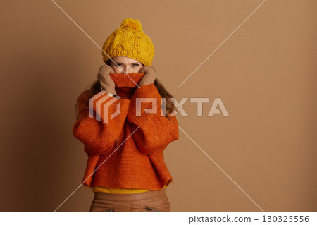 Playful Woman Hiding Face in Cozy Autumn Sweater 130325556