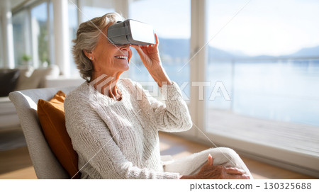 Concept of futuristic technology and fun from the elderly - Mature woman sitting on the sofa at home having entertainment and playing with virtual reality - Happy retired uses vr glasses 130325688