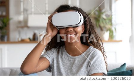 Cheery young african american lady in VR headset playing online game in virtual reality, driving imaginary car in neon light. Millennial black woman using auto simulator in cyberspace, collage 130326033